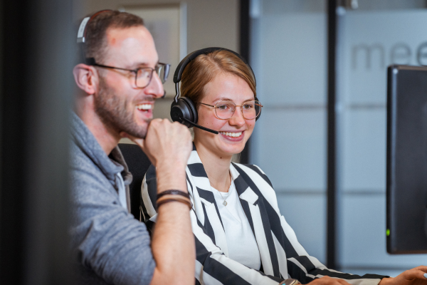 Zwei Mitarbeitende schauen auf einem Monitor